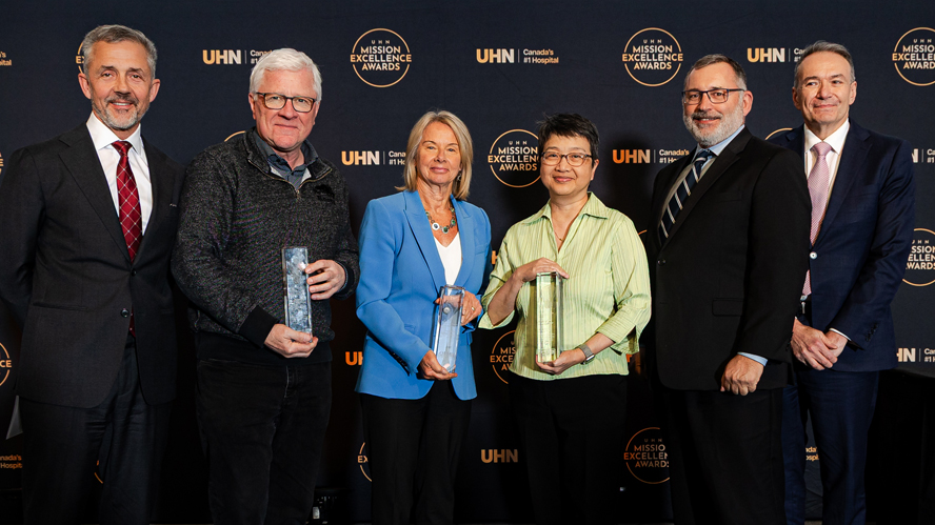 Group image with 4 smiling white males and 2 smiling women, one white and one Asian, all wearing business casual. The 3 in the center of the image (1 male and 2 females) are holding award trophies.
